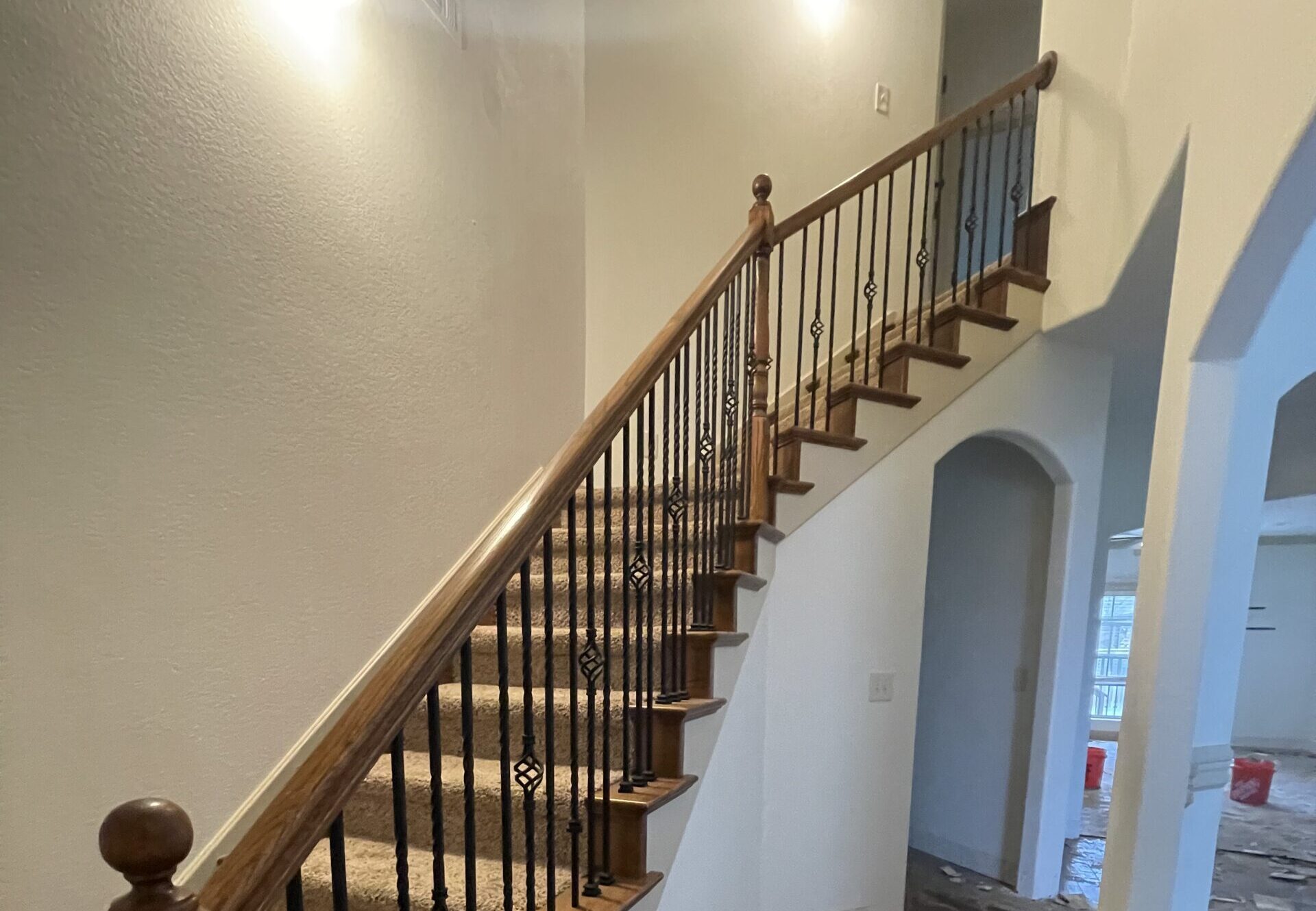 Staircase with wood treads and iron balusters in a space undergoing structural remodeling