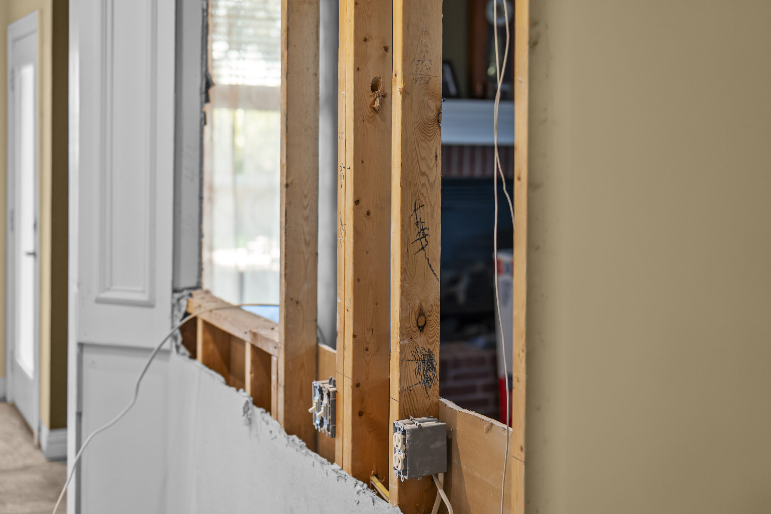 Wall opened to reveal wood studs and wiring during a structural remodel
