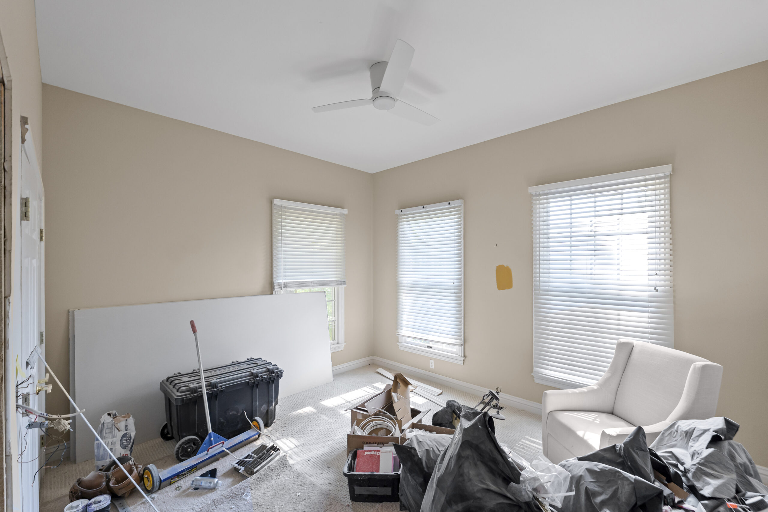 Freshly painted room with drop cloths, tools, and a chair staged during the final stage of a buildout