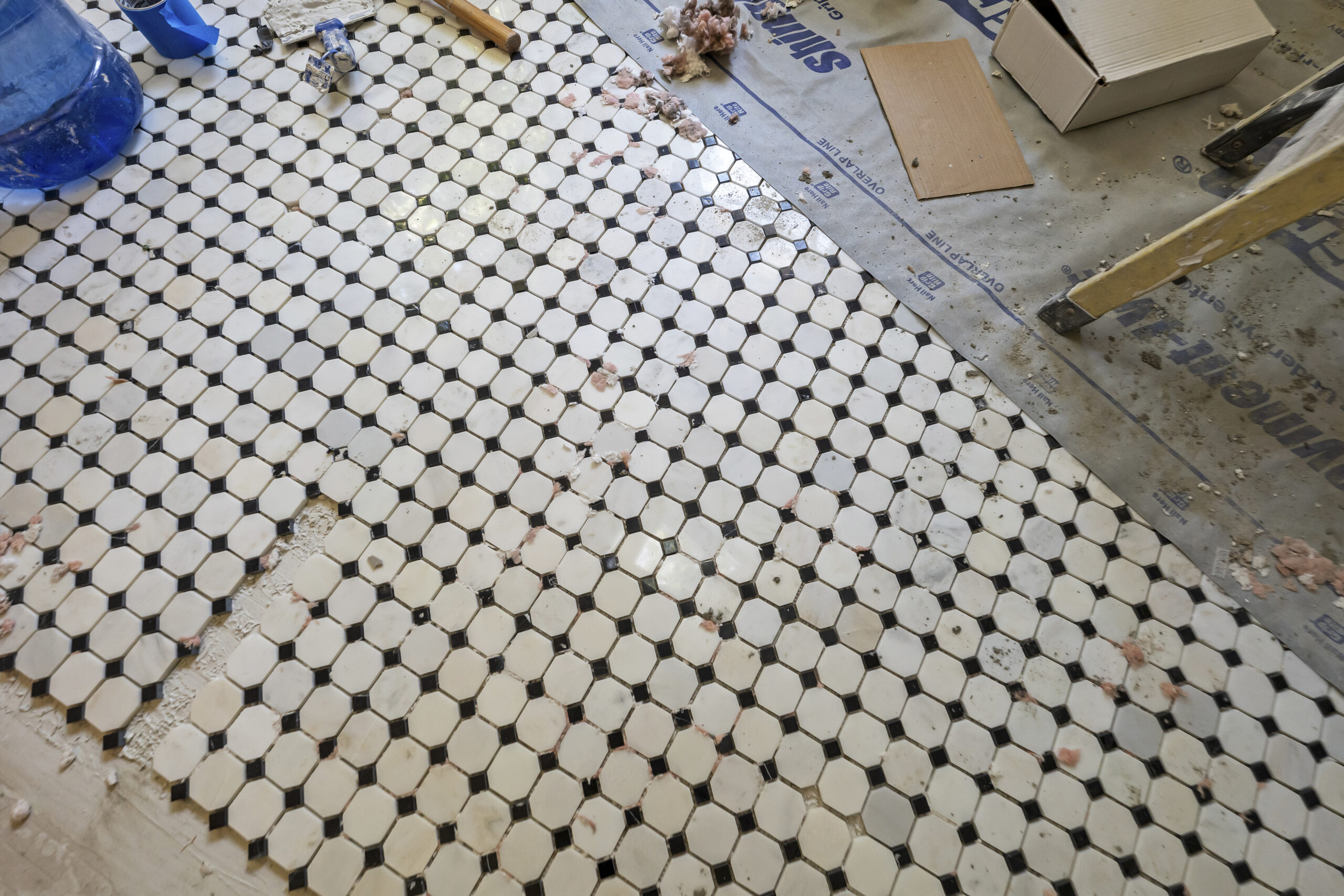 Black and white mosaic tile floor being installed as a custom finish detail