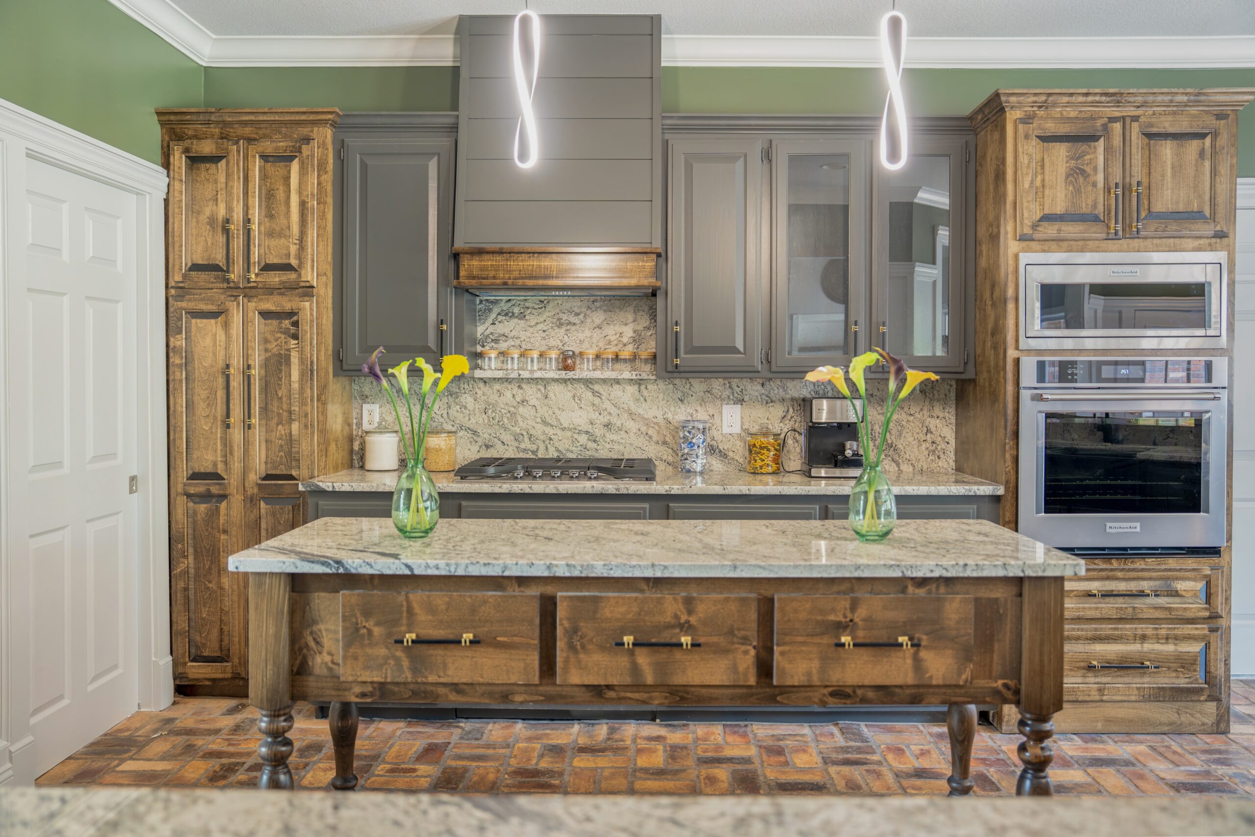 Remodeled kitchen with rustic wood cabinets, granite island, stainless wall ovens, and a tile backsplash