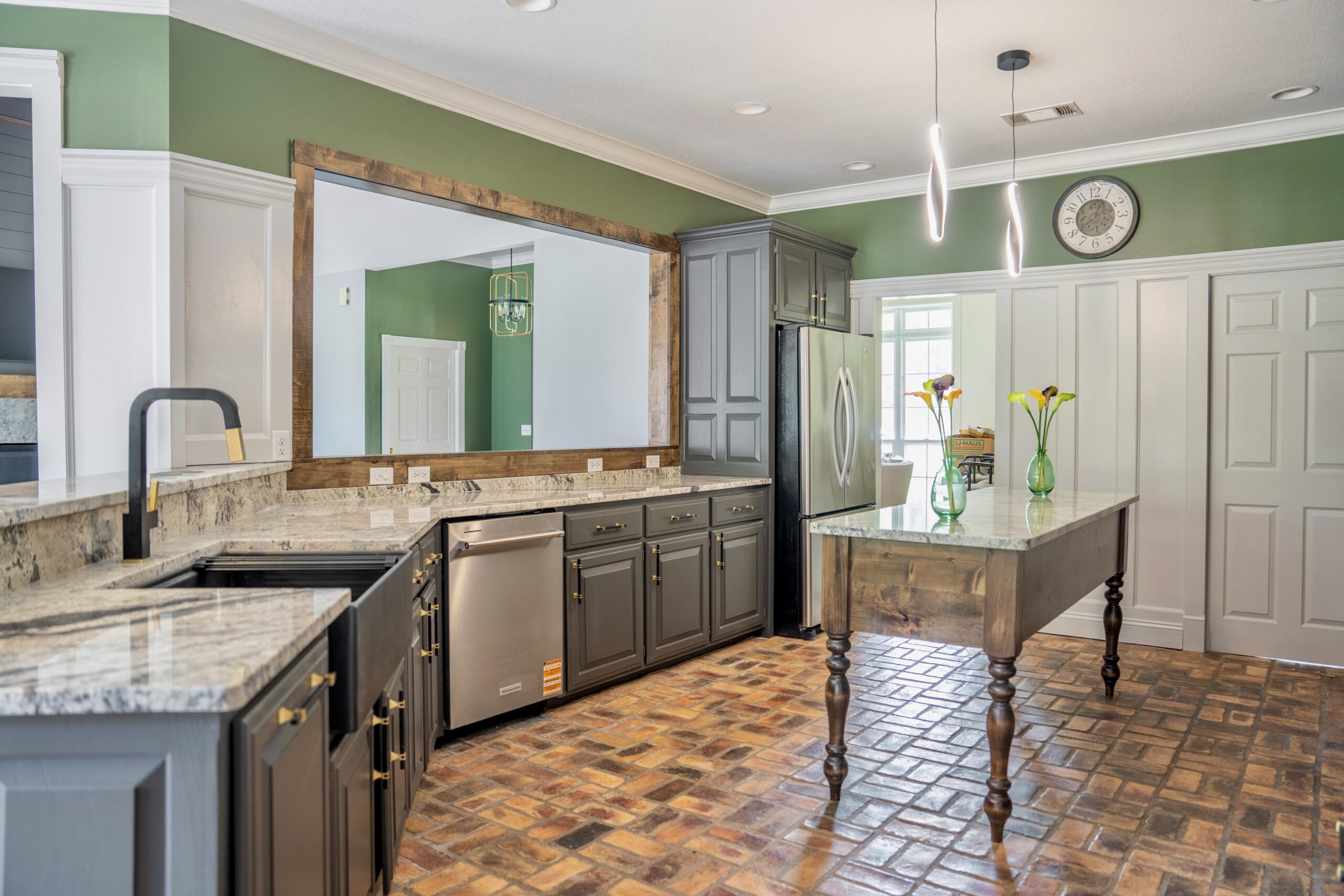 Renovated kitchen with green walls, white and gray cabinets, granite counters, brick-patterned floor, and a wood butcher block island